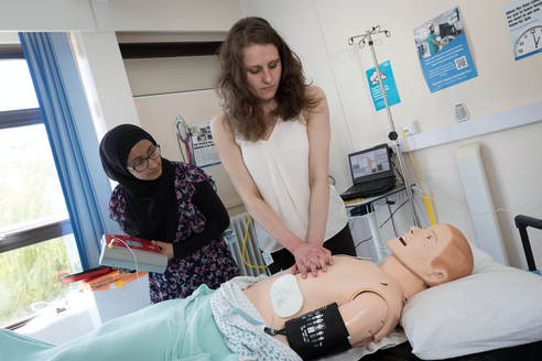 Photo. Two aspiring doctors practising resuscitation skills on patient simulator.