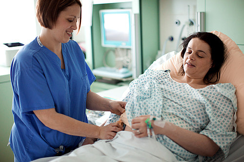 Photo. Midwife at bedside of patient.